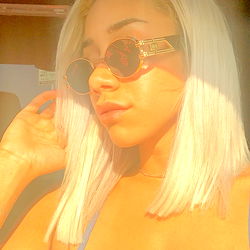 Fashion-forward female model Jazmine B Johnson posing for the camera in LA with a stylish short haircut, sunglasses and gold accessories. She is seen wearing a white top and blue denim shorts.