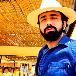 Asher Lopez in Casual Attire with Beard and Hat, Standing Outdoors