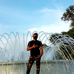 Alfredo Rodríguez, an individual in a park near a fountain, making a peace sign