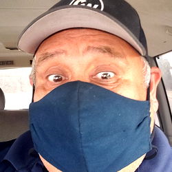 A Man Wearing a Face Mask and Hat in a Car