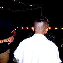 A lively night at a venue, with two men engaged in conversation. One man has tattoos, and the atmosphere appears to be casual and friendly.