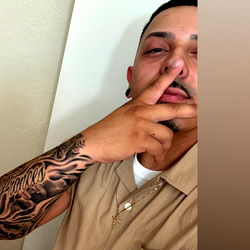 A Tattooed Man in a Tan Shirt Posting a Vibe on Social Media