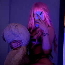 Model Ashley Silver in a vibrant room with purple lighting and a teddy bear