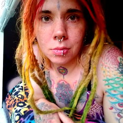 Vivid tattooed woman with dreadlocks and nose piercing, exuding a free-spirited vibe