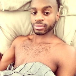 A shirtless man in a bed