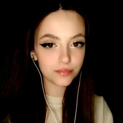 A young woman with long hair and headphones in her ears, posing for a photo.