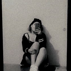 A young adult man poses in front of a mirror, capturing a candid moment with their phone.