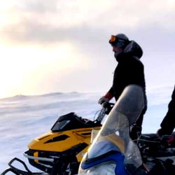Adventure on the Ice: Man Riding a Snowmobile in a Winter Landscape