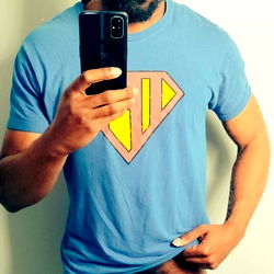 Onlyfans model ChamosBrave takes a playful pose with a Superman T-shirt