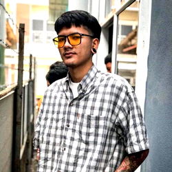 A Man in a Plaid Shirt and Sunglasses Standing by a Fence