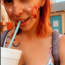 A woman enjoying a drink with glitter face paint