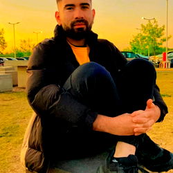 A person posing for a photo on a concrete block outdoors