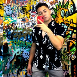 Young man posing in front of a graffiti-covered wall with a colorful phone case.