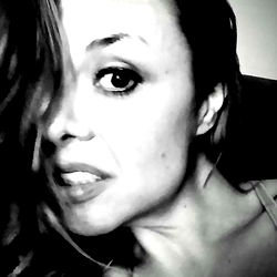 A woman with dark hair and makeup looking to the side