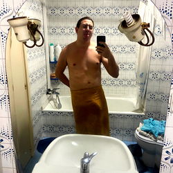Shirtless man in bathroom mirror