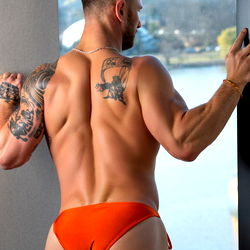 Fit Bodybuilder in Orange Bikini with Tattoos on Display,