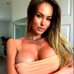 Beautiful blonde model in a bathroom mirror with pink dress and red hair