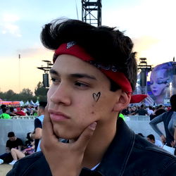 Aleeks, young man in red bandana and blue jeans, at concert with contemplative expression.