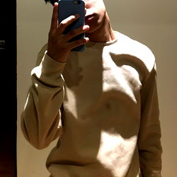 Fashionable Teenage Boy with Phone, Tan Sweater, and Neutral Background