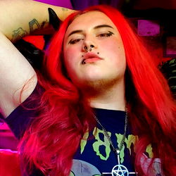 Long-haired individual in a relaxed pose, possibly a musician or performer