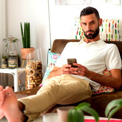 Casually Sitting Man, 35, Engaging with Phone