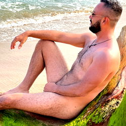 Ajimenez, a Puerto Vallarta-based model, in a casual, shirtless pose on a beach.