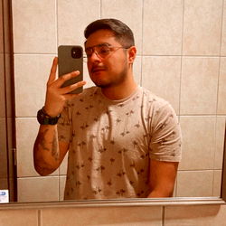 A Young Man in a T-Shirt, Taking a Selfie in the Mirror of a Public Restroom