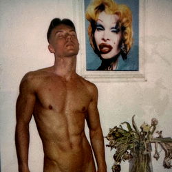 Austin, the muscular model, strikes a pose in front of a Marilyn Monroe painting