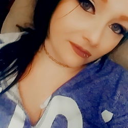 Amy Johnson, an OnlyFans model with striking red hair and tattoos, shares a personal moment on her platform. Her blue eyes stand out against the vibrant backdrop of her profile.