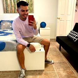 Young Man in White Sneakers Sitting on Bed