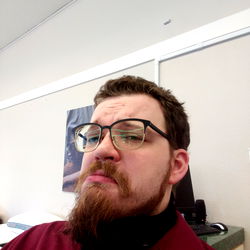Bearded Man in Glasses with Beard and Mustache, Sitting at Desk
