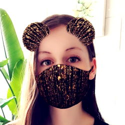 Amelia, a 21-year-old woman with a unique style, showcasing her playful personality with the adorable bear face mask and a touch of sparkle in her eyes. She's a fan of fun and quirky accessories, like the black and gold mask she's wearing.
