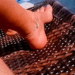 A woman's foot rests on a poolside lounge chair