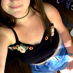 Alexandra, a young adult female with blue eyes and light skin posing in a tank top and shorts.