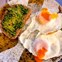 Breakfast with Avocado Toast, Fried Eggs, and Egg Benedict on a Gray Plate