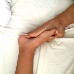 Hand Holding Feet on Bed