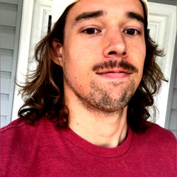 Andrew Umphreak, an OnlyFans model in a red shirt and beard