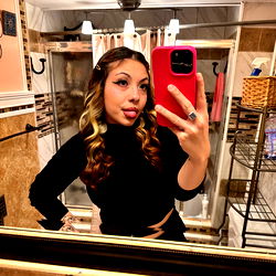 A young woman taking a selfie in front of a bathroom mirror