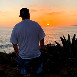 Man Standing Overlooking Ocean at Sunset