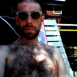 Shirtless Man with Chest Hair, Sunglasses, and Shorts on Beach Chair