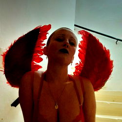 A model in a red feathery angel costume, striking a pose