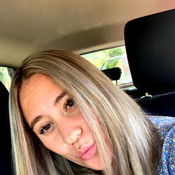 Aimee, a young woman with short blonde hair posing for the camera in a car.