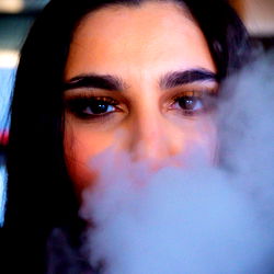 A model posing with a cloud of smoke from a vape device.