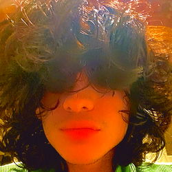 Long-haired individual in a cozy setting, possibly a restaurant or cafe