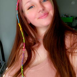 A woman with a colorful hairpiece and piercings, posing for the camera.