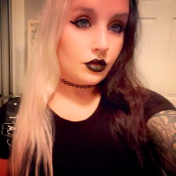 Woman in Dark Room with Black Hair, Tattoos, and Eye Makeup