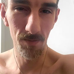 A Shirtless Man with a Beaded Necklace in a Bathroom Mirror