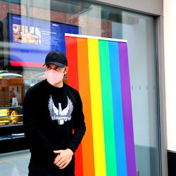 Max Herzberg, a Dresden-based model standing in front of a rainbow flag