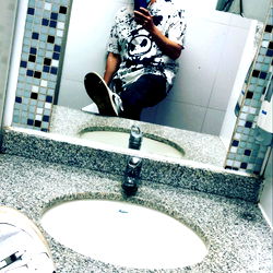 A person taking a mirror selfie in a public restroom