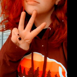 Red-haired OnlyFans model Aubrn celebrates with a peace sign